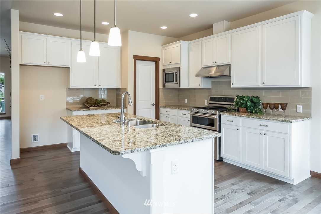 5463 Shields Road Ferndale, WA 98248 - Photo 15 of 17 a kitchen with kitchen island granite countertop wooden cabinets and white appliances