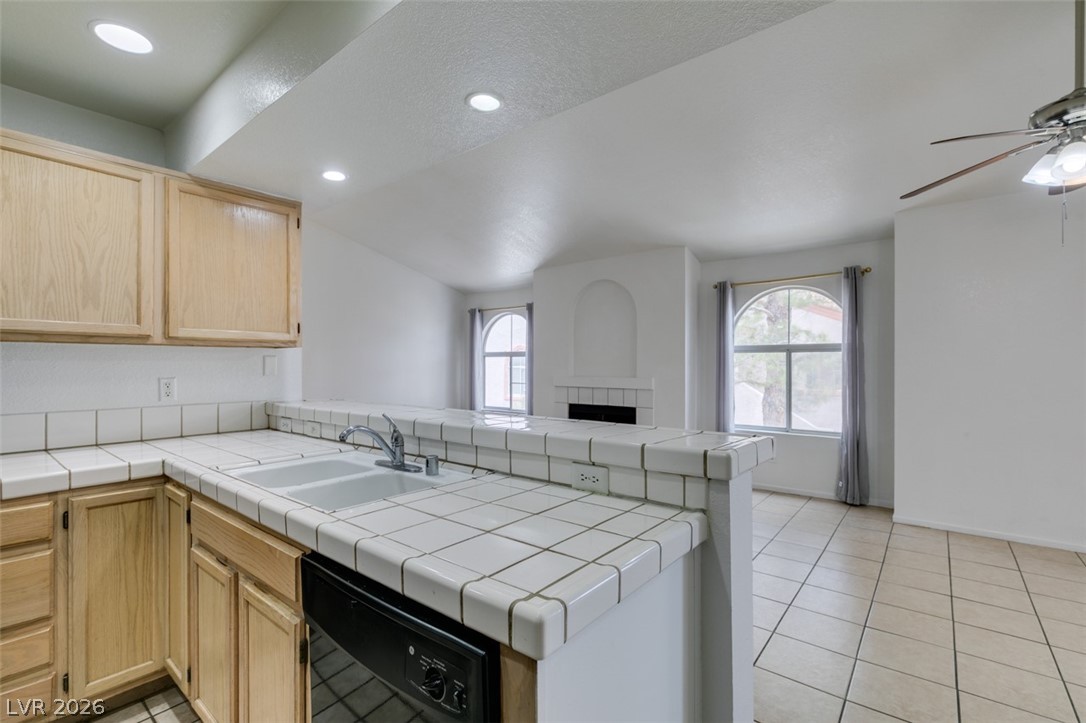 7570 West Flamingo Road, Unit 252 Las Vegas, NV 89147 - Photo 25 of 44 A functional kitchen with tile counters overlooks a comfortable living area, ideal for entertaining.
