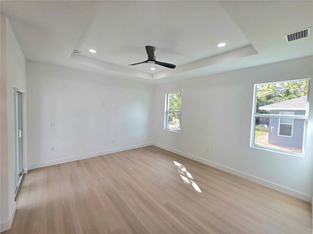 2967 Barry Road North Port, FL 34286 - Photo 4 of 19 an empty room with wooden floor ceiling fan and windows