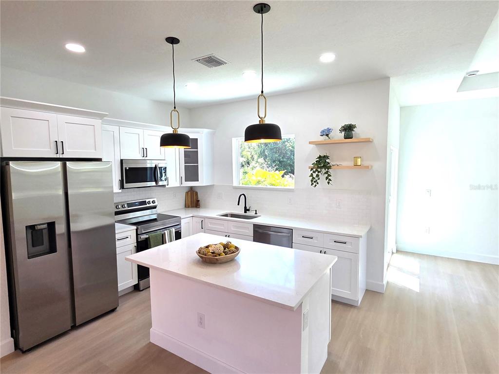 2967 Barry Road North Port, FL 34286 - Photo 6 of 19 a kitchen with a refrigerator a stove a sink and a wooden floor