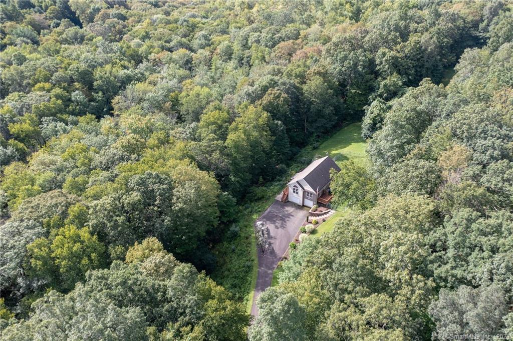 an aerial view of residential house with outdoor space and trees all around
