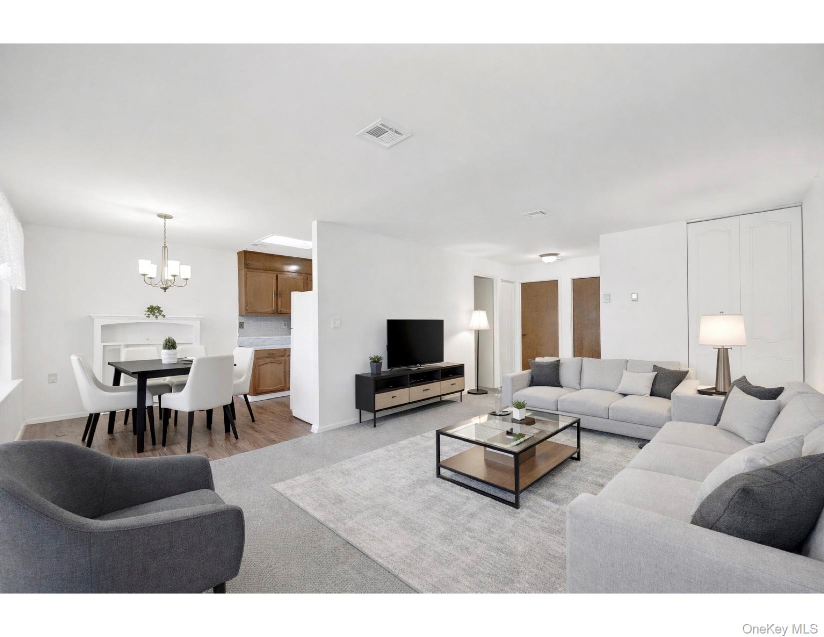 279 Berwick Court, Unit B Ridge, NY 11961 - Photo 7 of 13 a living room with furniture a table and a flat screen tv