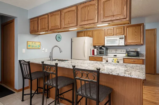 a kitchen with stainless steel appliances granite countertop a table chairs sink and cabinets