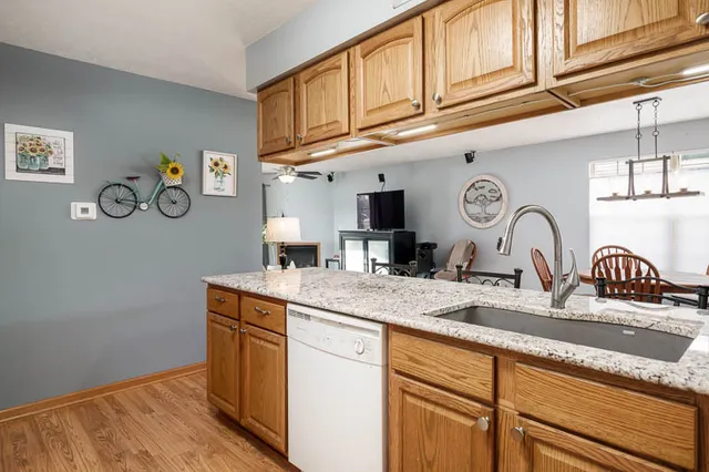 a kitchen with kitchen island granite countertop a sink cabinets and wooden floor