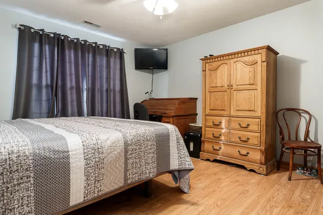 a bedroom with a bed and a flat tv screen on dresser