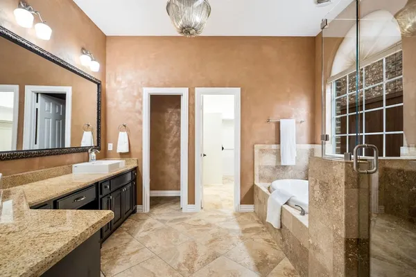 a spacious bathroom with a tub sink and mirror