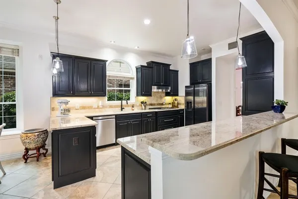 a large kitchen with stainless steel appliances kitchen island granite countertop a sink stove and refrigerator