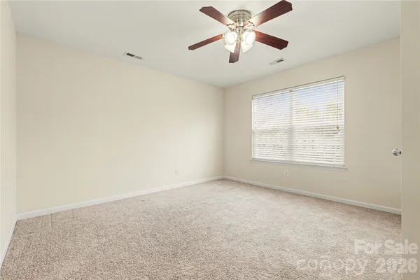 an empty room with a chandelier fan and windows