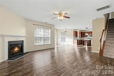 a view of an empty room with wooden floor fireplace and a window