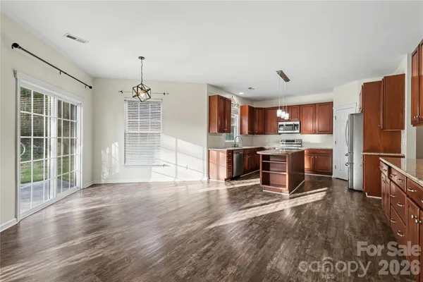 a kitchen with stainless steel appliances granite countertop a refrigerator oven a sink dishwasher and a stove with wooden floor