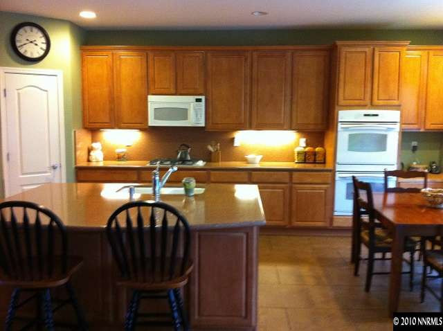 530 Secretariat Court Reno, NV 89521 - Photo 7 of 13 a kitchen with granite countertop a stove a sink dishwasher a dining table and chair with wooden floor