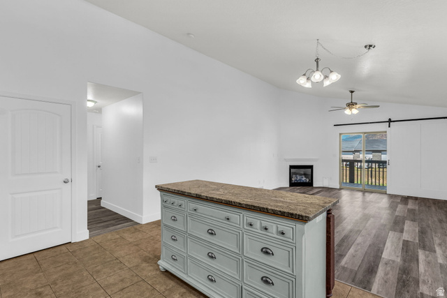 1836 West 800 North Mapleton, UT 84663 - Photo 8 of 38 Kitchen island with a stone-finish countertop, featuring a built-in electric fireplace, vaulted ceilings, and wood-finish flooring