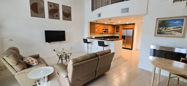 a living room with furniture a flat screen tv and kitchen view