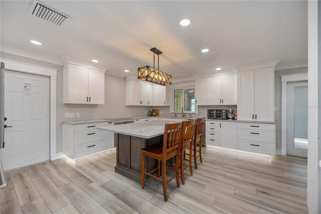 3254 Elliott Street Venice, FL 34292 - Photo 3 of 23 a kitchen with kitchen island granite countertop a sink cabinets and wooden floor
