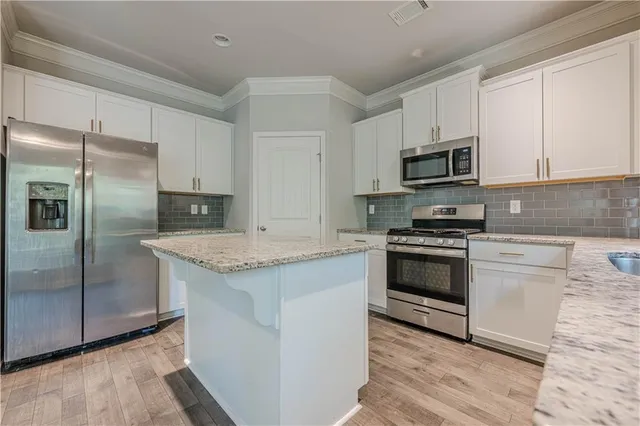 a kitchen with kitchen island granite countertop a sink appliances and cabinets