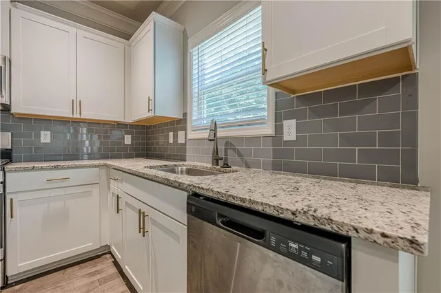 a kitchen with granite countertop a sink and white cabinets