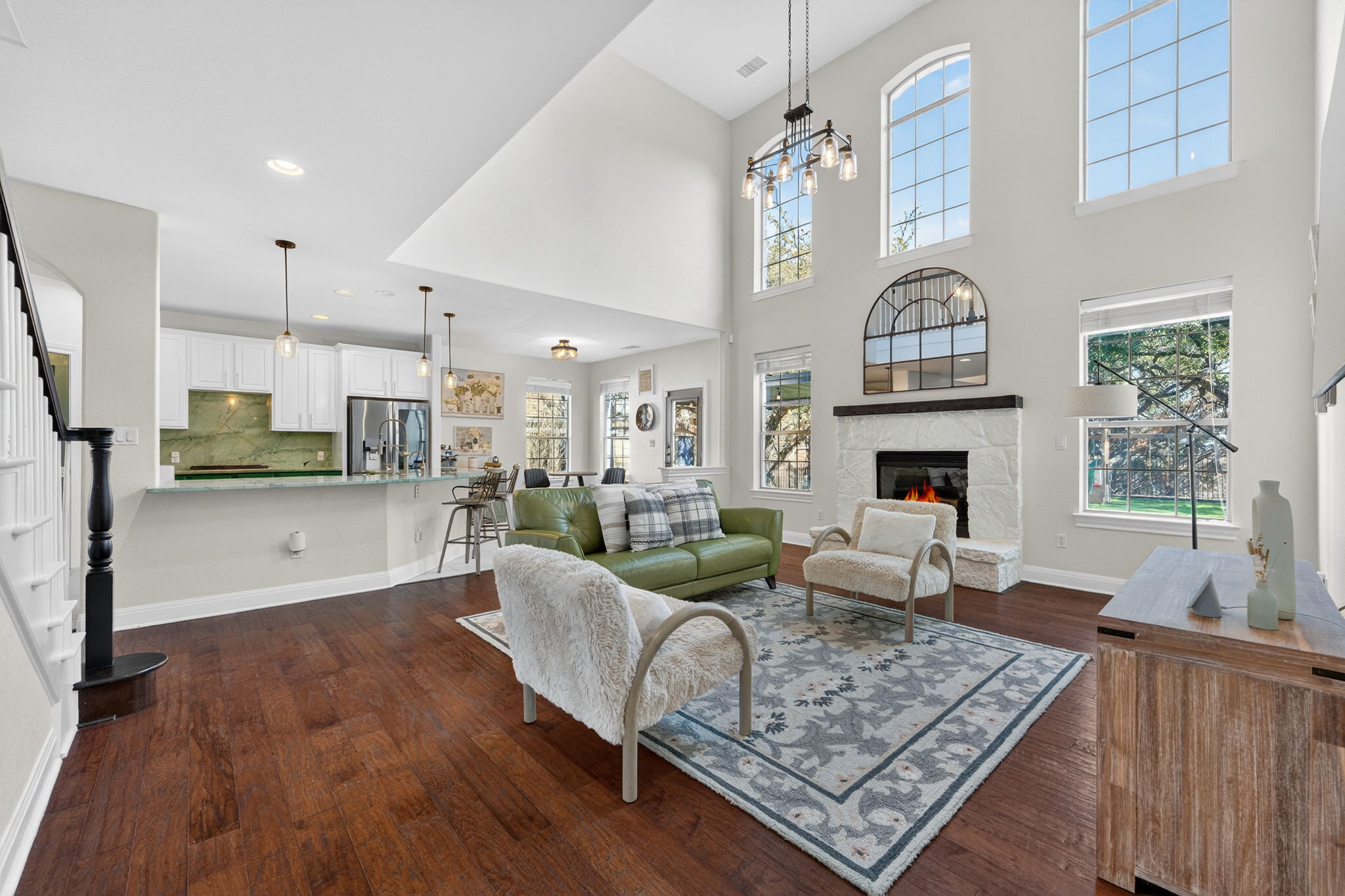 117 Lakota Pass Austin, TX 78738 - Photo 2 of 18 Enjoy an open-concept living room, kitchen, and breakfast area featuring soaring two-story ceilings, a cozy fireplace, and abundant natural light throughout.
