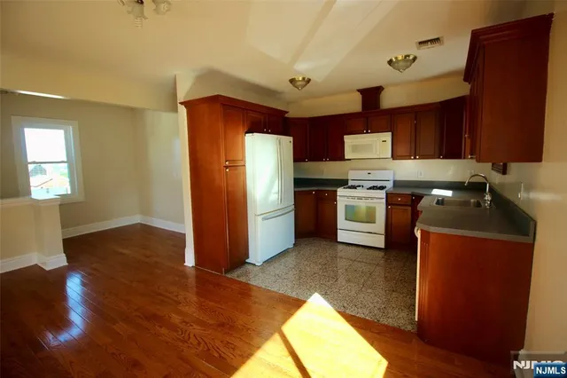 a kitchen with stainless steel appliances granite countertop a refrigerator a sink dishwasher a stove with wooden cabinets and floor