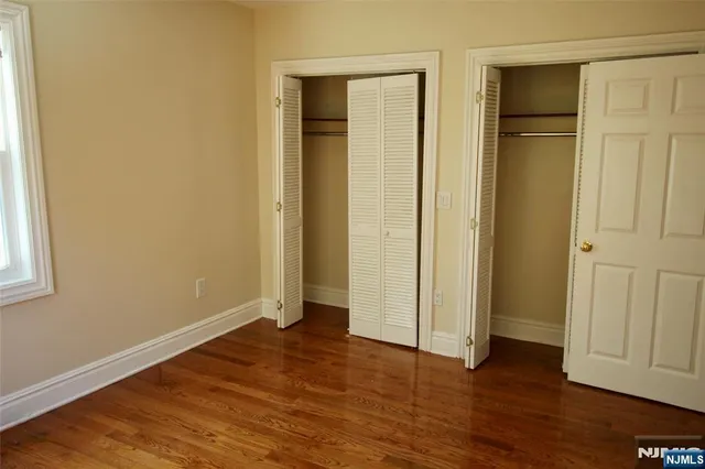 an empty room with wooden floor and closet area