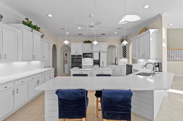 a large kitchen with stainless steel appliances a large counter top a stove a chimney a sink and dining room view