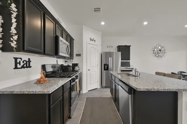 a kitchen with granite countertop kitchen island stainless steel appliances a sink stove and refrigerator