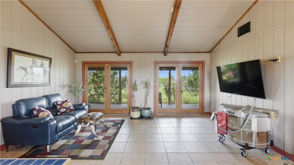 127 Offer Llano, TX 78643 - Photo 11 of 40 Spacious interior featuring a vaulted ceiling with exposed wood beams, vertical wall paneling, and ceramic tile flooring