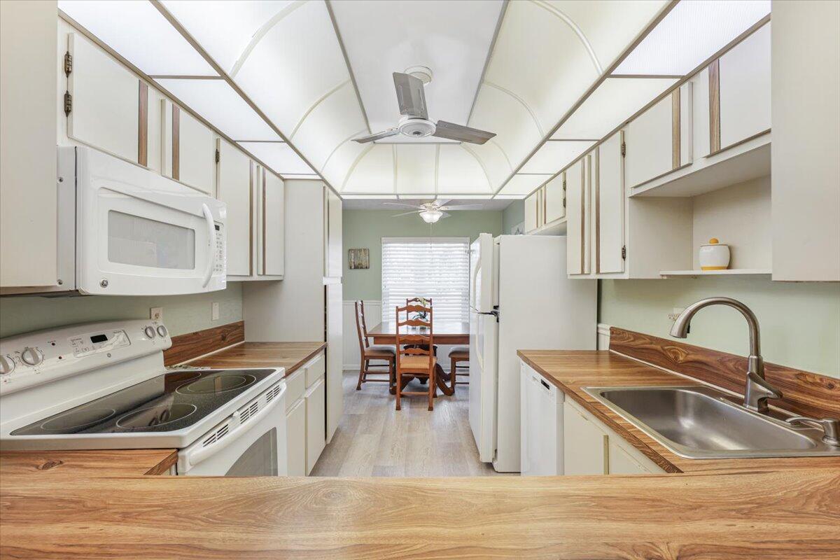 5178 Privet Place, Unit D Delray Beach, FL 33484 - Photo 11 of 41 a kitchen with stainless steel appliances granite countertop a sink dishwasher and white cabinets with wooden floor