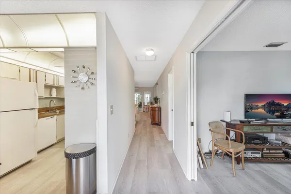 a view of a hallway with furniture and a refrigerator