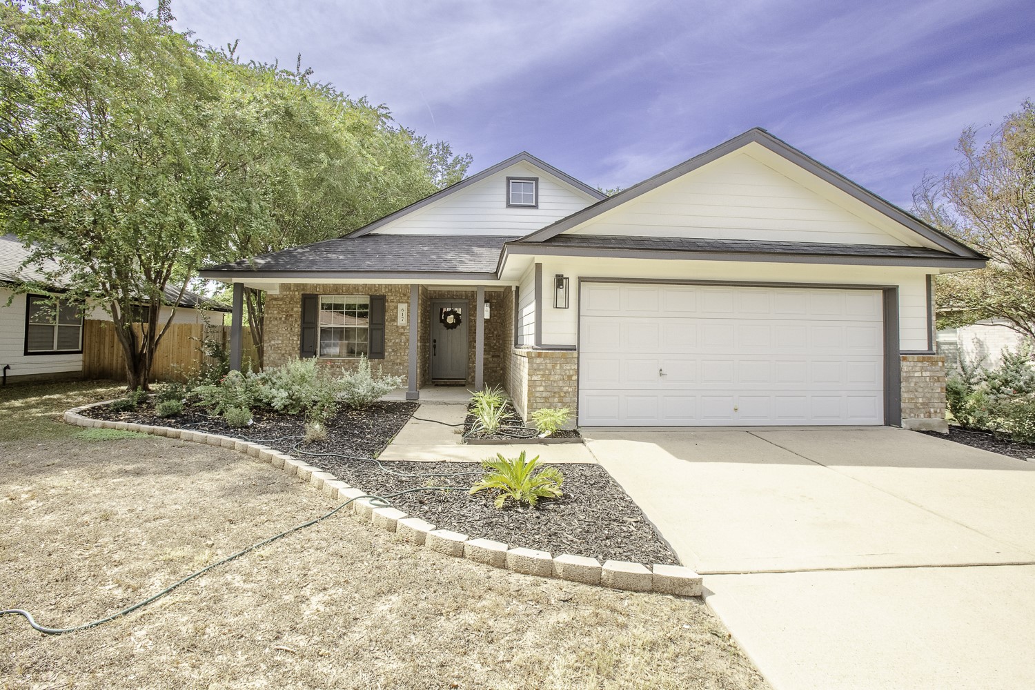 View of front of property with brick siding, covered porch, concrete driveway, a shingled roof, and an attached garage