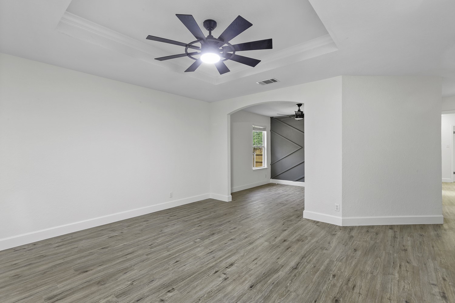 617 Barbara Way Bastrop, TX 78602 - Photo 17 of 39 Spare room featuring a tray ceiling, light wood finished floors, arched walkways, a ceiling fan, and ornamental molding