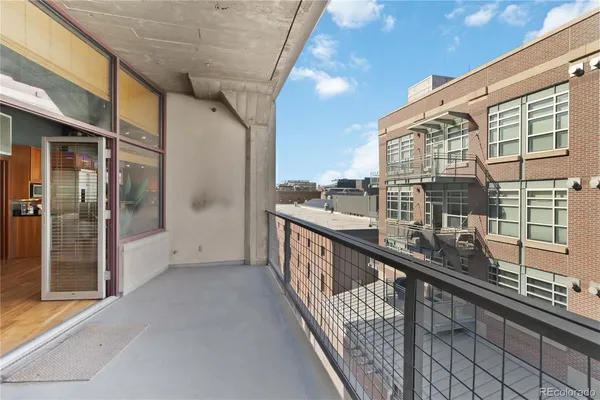 a view of balcony with a couple of cars parked in parking lot