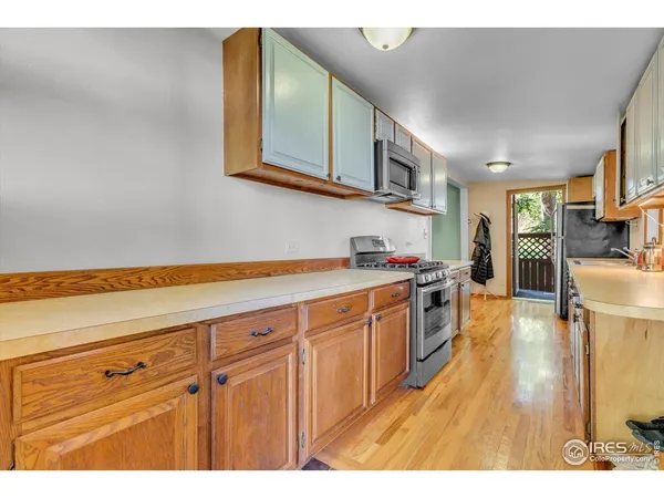 a kitchen with stainless steel appliances granite countertop a sink dishwasher stove and cabinets with wooden floor