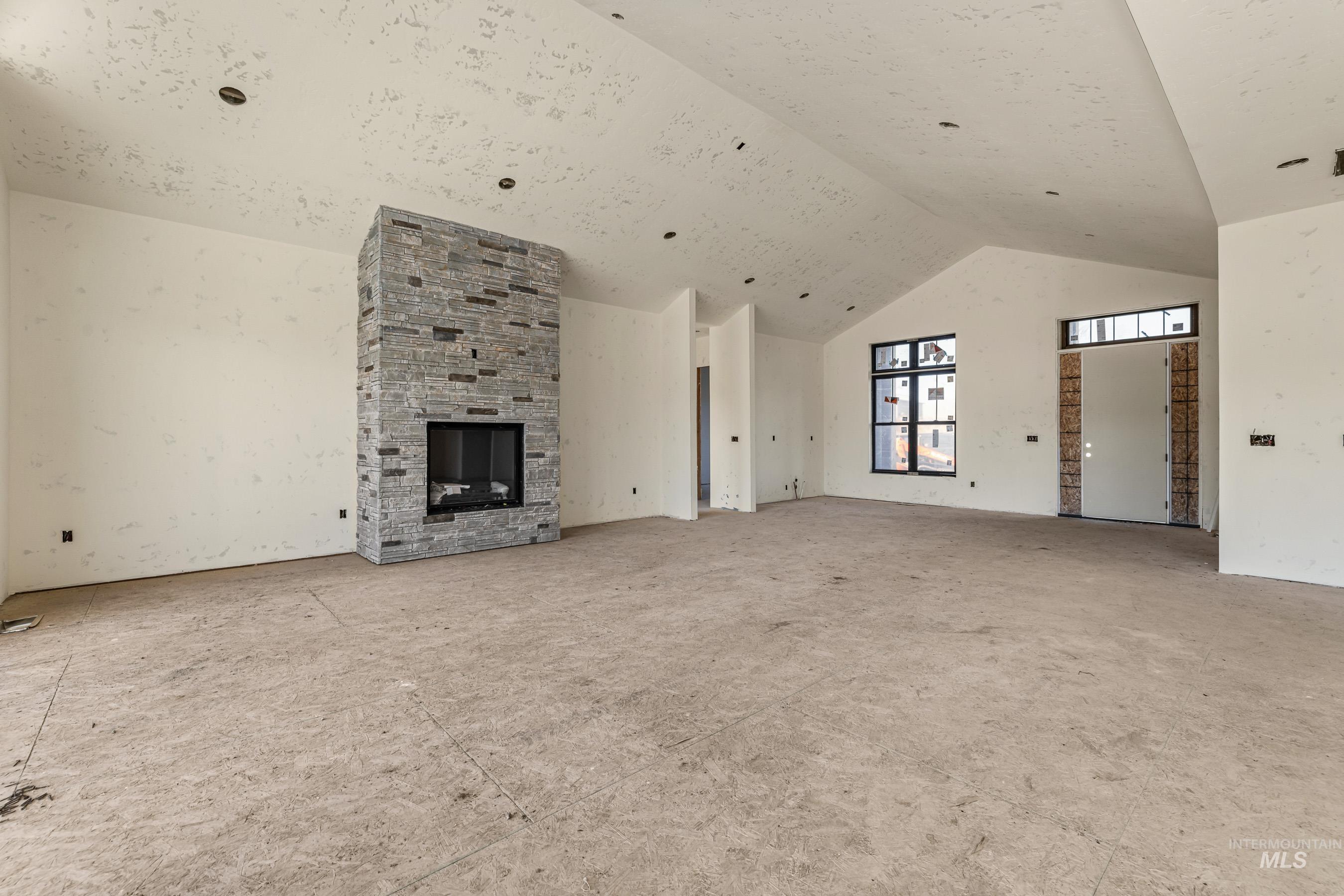 13910 Sky View Court, Unit 8 McCall, ID 83638 - Photo 24 of 40 Unfurnished living room with high vaulted ceiling and a stone fireplace