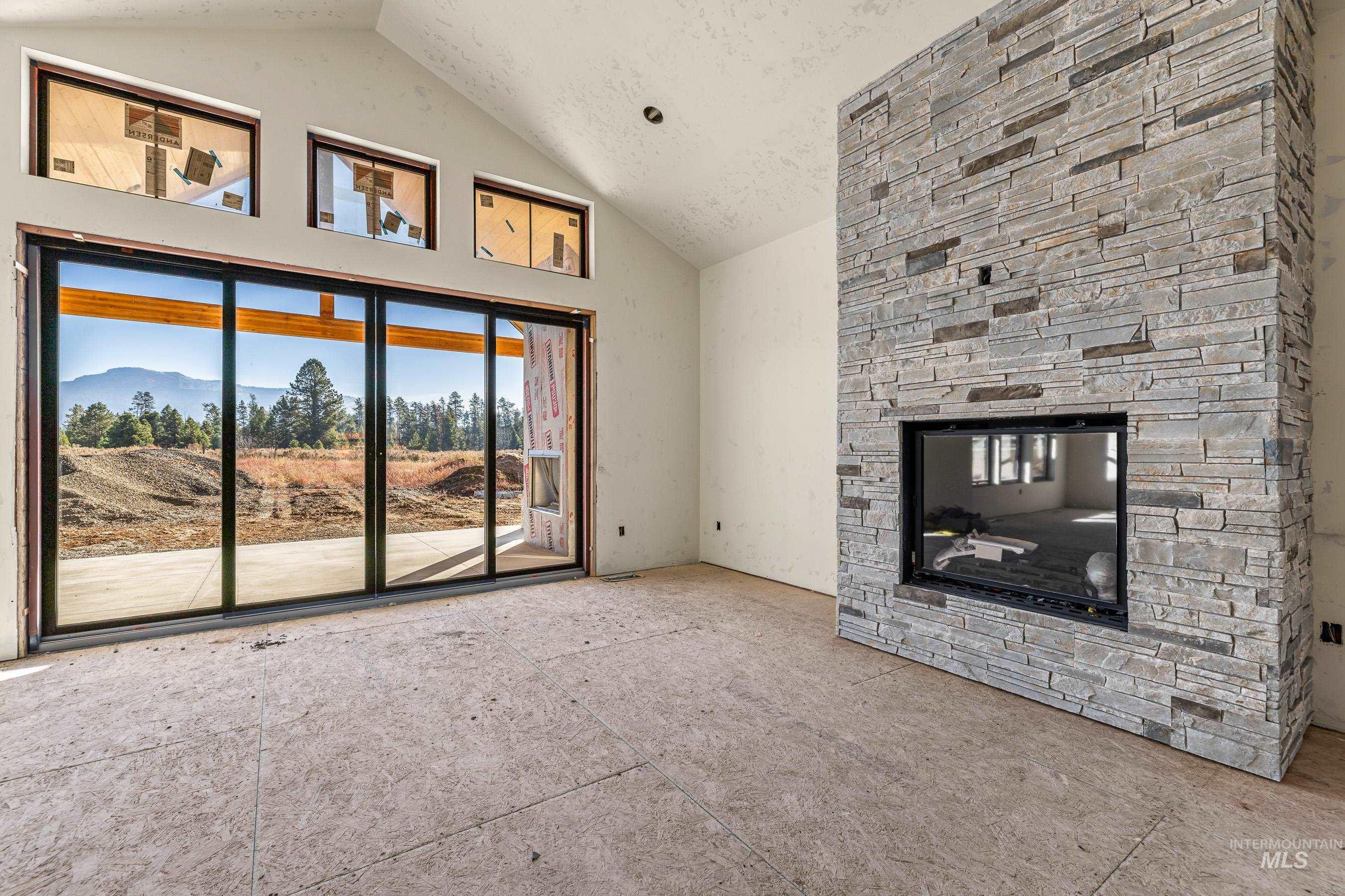 13910 Sky View Court, Unit 8 McCall, ID 83638 - Photo 4 of 40 Unfurnished living room featuring a stone fireplace, high vaulted ceiling, and a mountain view