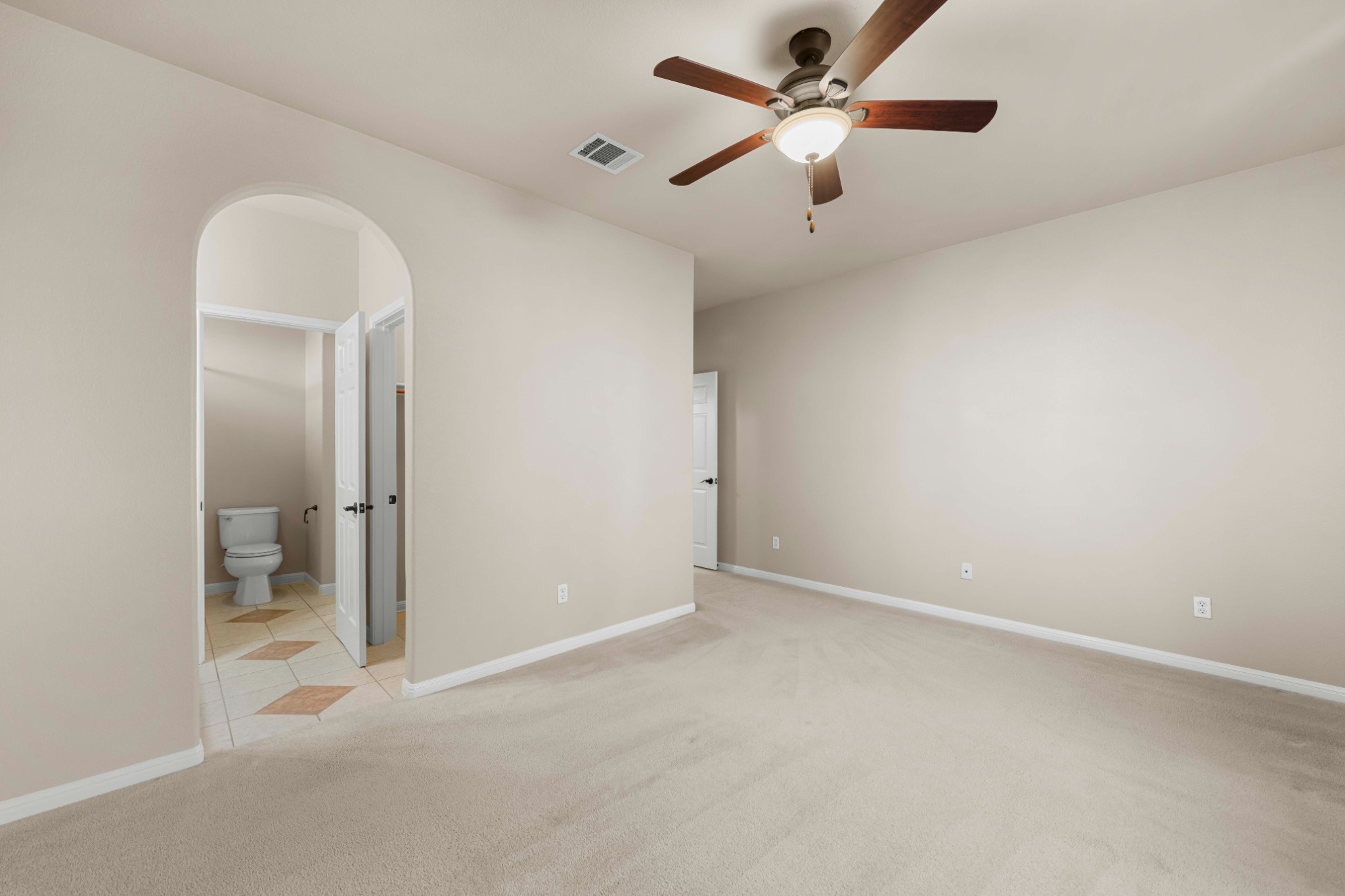 3903 Remington Road Cedar Park, TX 78613 - Photo 21 of 29 A spacious room offers comfortable carpet flooring and an arched doorway leading to a well-appointed private bath.