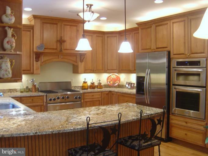 16820 Whites Store Road Boyds, MD 20841 - Photo 7 of 30 a kitchen with stainless steel appliances granite countertop a stove a refrigerator and a dining table with wooden floors