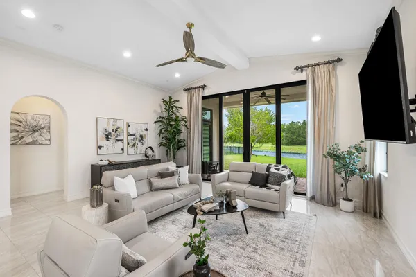 a living room with furniture a flat screen tv and a floor to ceiling window
