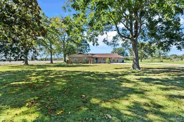 a view of a house with a big yard and large trees