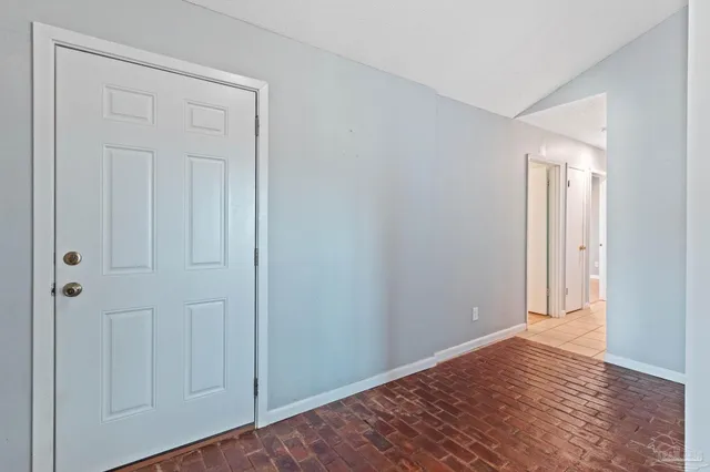 a view of an empty room with window and a kitchen