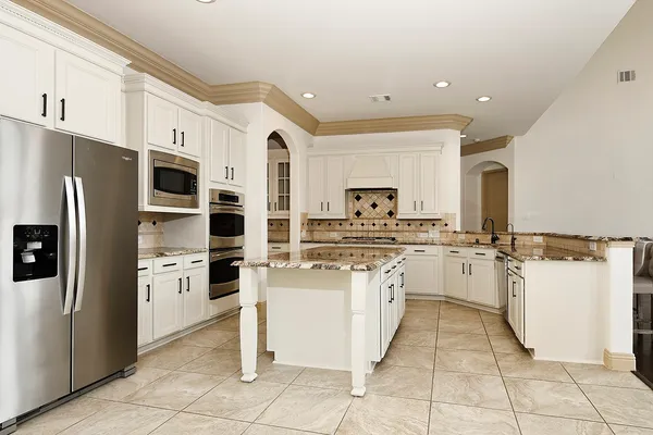 a kitchen with stainless steel appliances granite countertop a refrigerator and a stove top oven