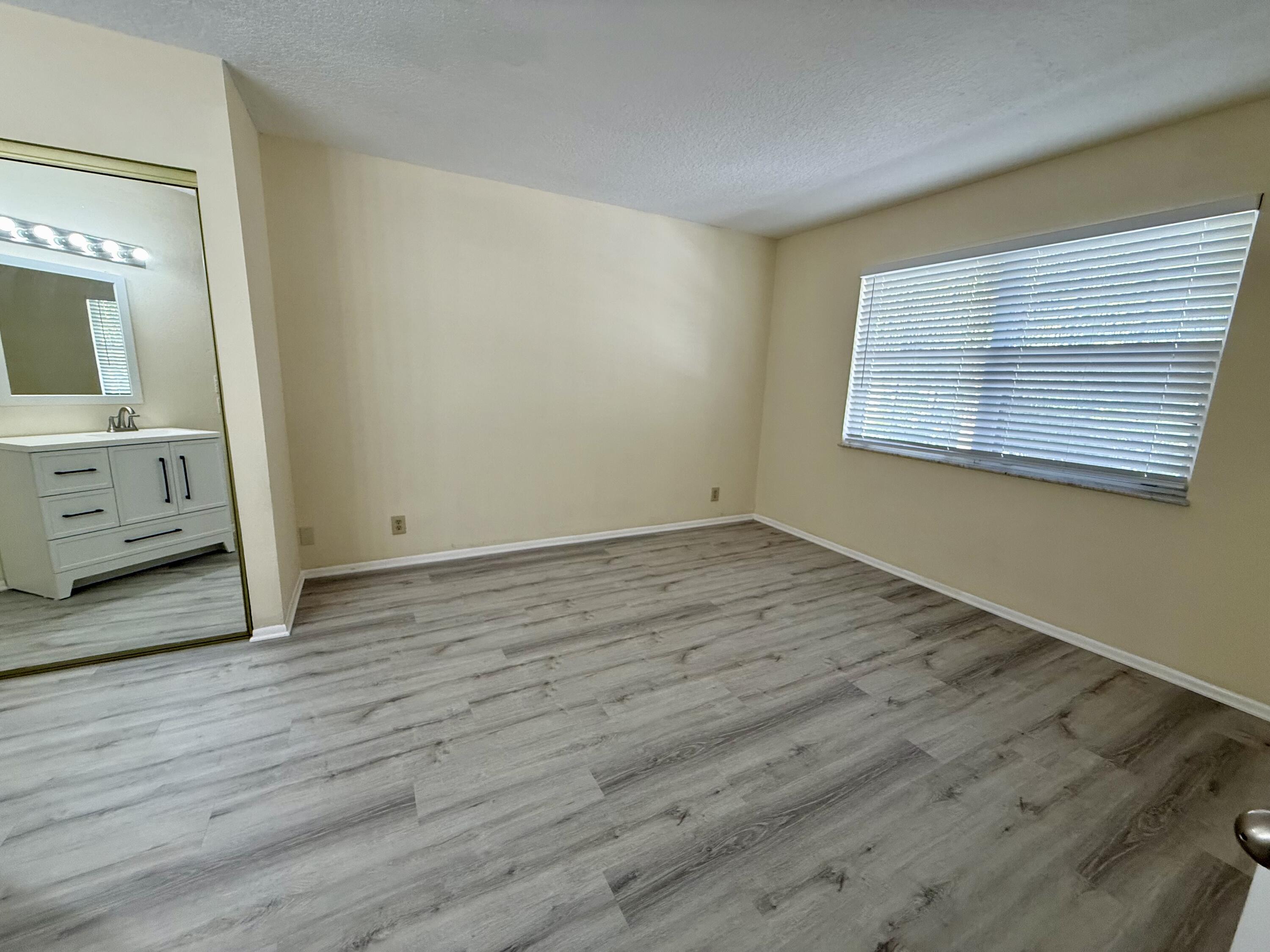 1520 Southeast Royal Green Circle, Unit K 205 Port St. Lucie, FL 34952 - Photo 12 of 18 a view of an empty room with wooden floor and a window