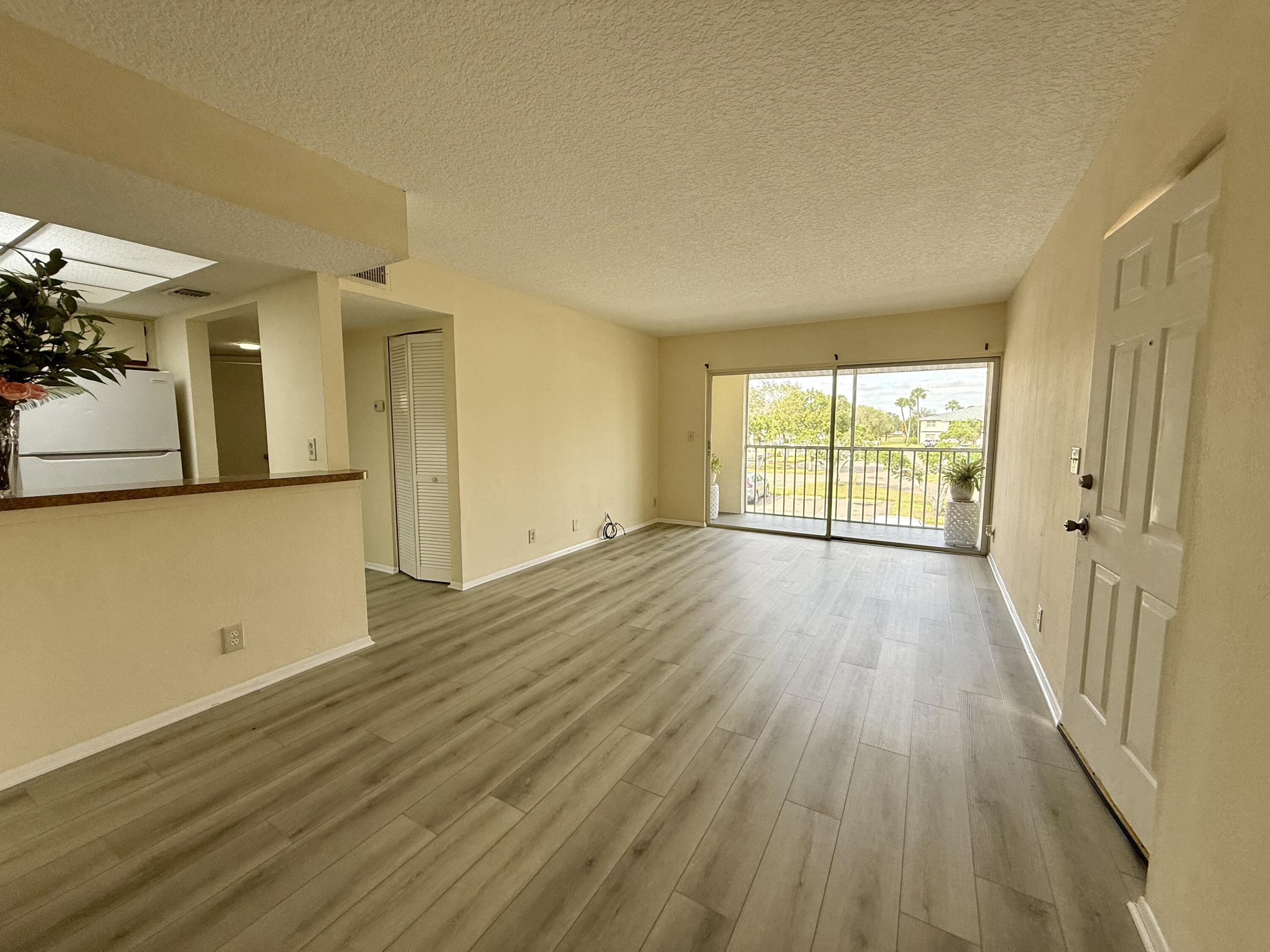 1520 Southeast Royal Green Circle, Unit K 205 Port St. Lucie, FL 34952 - Photo 2 of 18 an empty room with wooden floor and windows
