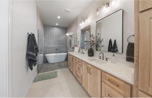 a bathroom with a double vanity sink a mirror and a bathtub