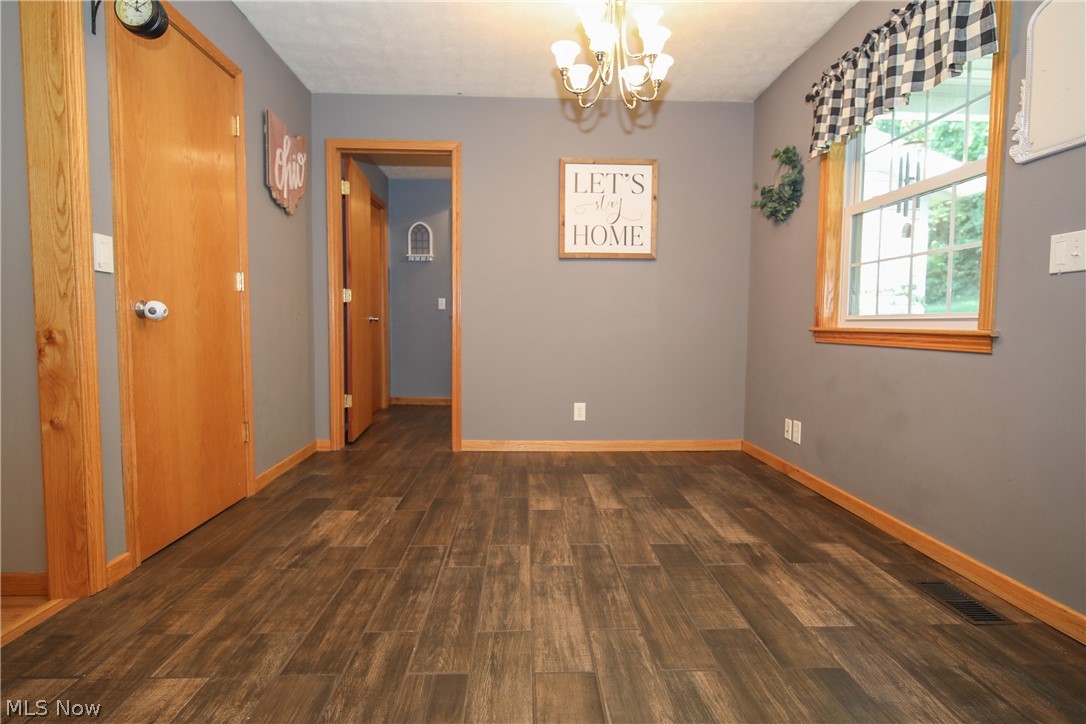 38610 Spiedel Town Road Bethesda, OH 43719 - Photo 11 of 33 Unfurnished room with an inviting chandelier and dark hardwood / wood-style floors