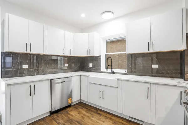 a kitchen with white cabinets sink and window
