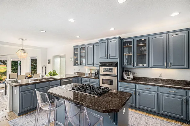 a kitchen with stainless steel appliances granite countertop a stove top oven a sink a dining table and chairs