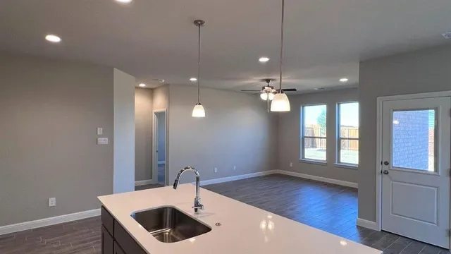 a kitchen with kitchen island granite countertop a sink a counter top space stainless steel appliances and cabinets