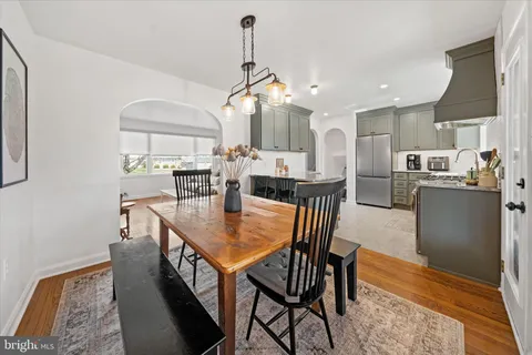 a dining room with stainless steel appliances kitchen island granite countertop a table chairs and a refrigerator