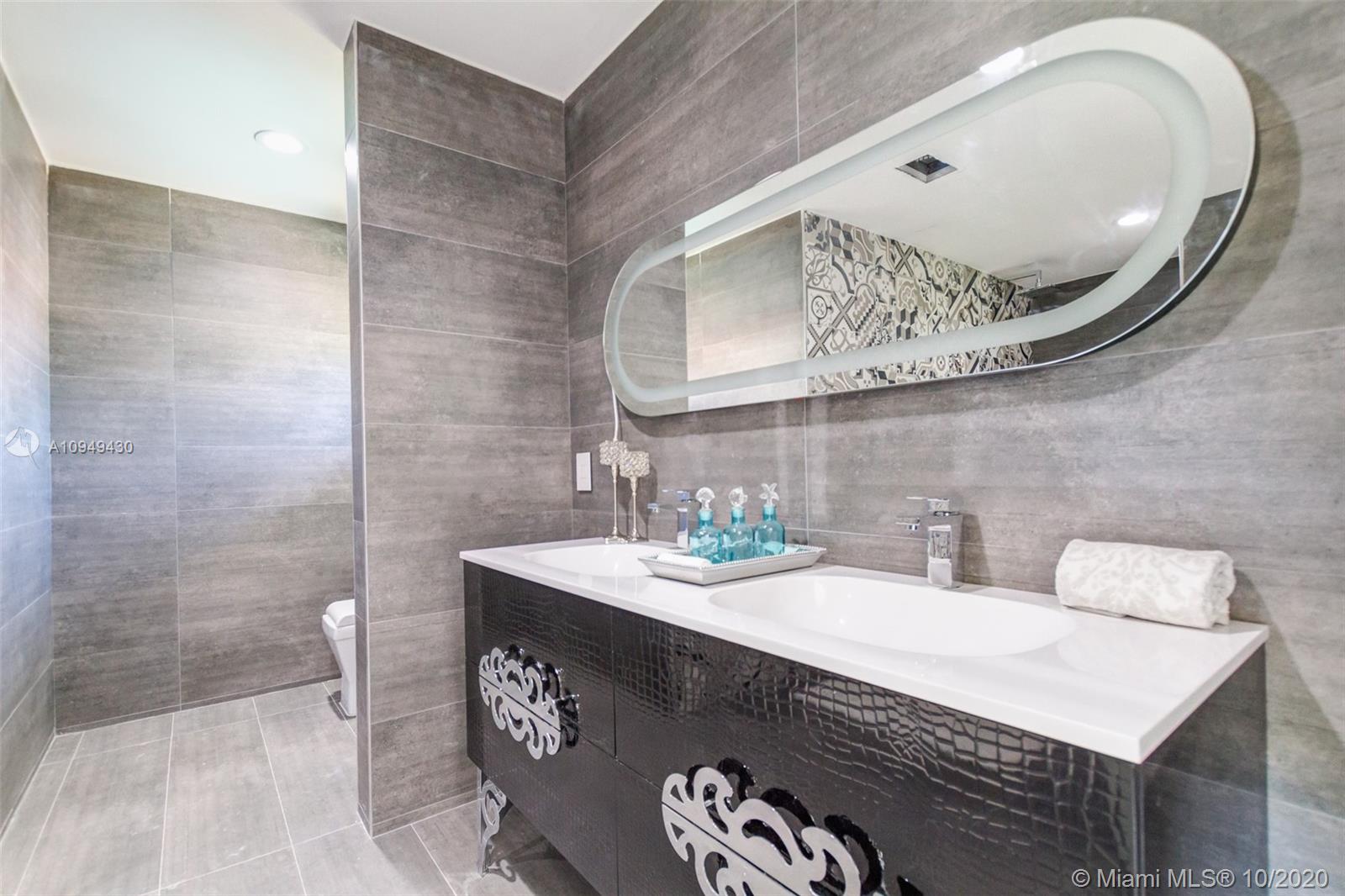 6030 Alton Road Miami Beach, FL 33140 - Photo 25 of 51 a bathroom with a sink a mirror and a toilet