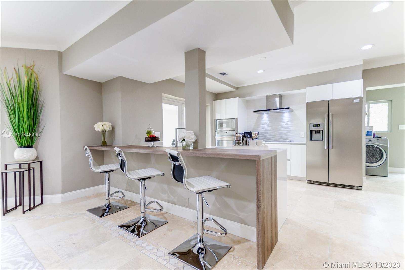 6030 Alton Road Miami Beach, FL 33140 - Photo 8 of 51 a kitchen with stainless steel appliances kitchen island granite countertop a refrigerator and a stove top oven